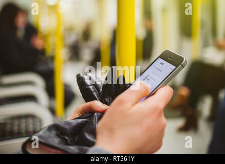 Woman using smartphone telephone inside metro tube station underground with map navigation aplication on the screen open and searching for the next destination - wagon interior Stock Photo