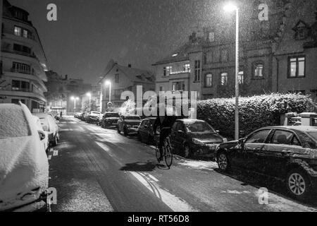 STRASBOURG, FRANCE - DEC 3 2017: Deliveroo delivery bike in French city cycling fast for food delivery on time on a cold winter snowy night in residential neighborhood Stock Photo