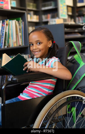 Disabled schoolgirl reading a book in the classroom Stock Photo