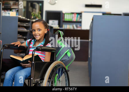 Disabled schoolgirl reading a book in the classroom Stock Photo