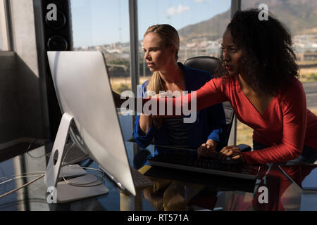 Female executives working on desktop pc at desk in office Stock Photo