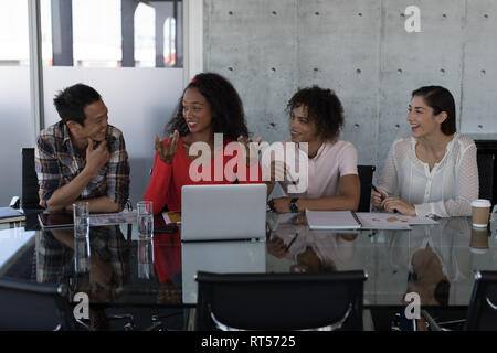 Happy executives talking with each other at table in office Stock Photo