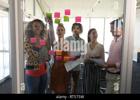 Business colleagues discussing over sticky notes in office Stock Photo