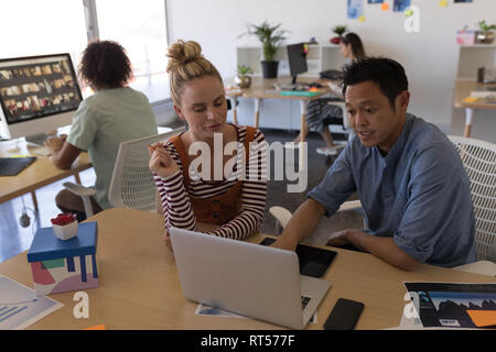 Business colleagues discussing over laptop in office Stock Photo