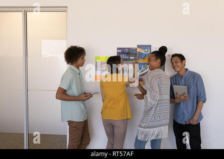 Business colleagues discussing over graphs and sticky notes in office Stock Photo