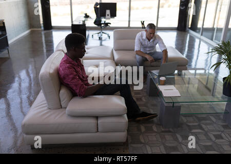 Male executives using laptop and digital tablet in office Stock Photo