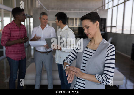 Female executive checking time on smartwatch in office Stock Photo