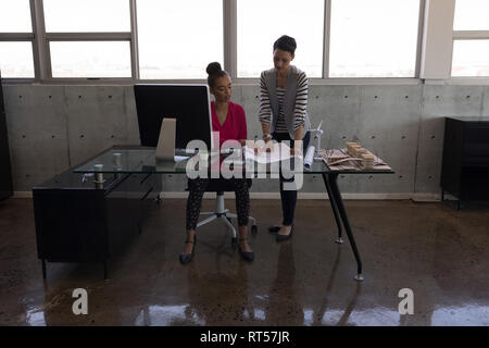 Female executives discussing over blueprint at desk Stock Photo