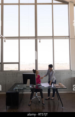 Female executives discussing over blueprint at desk Stock Photo
