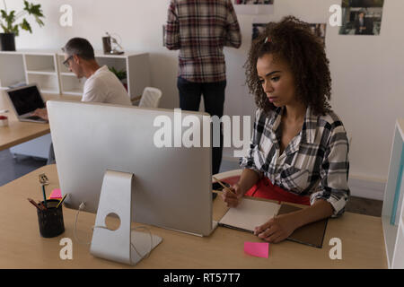 Female executive writing on diary at desk Stock Photo