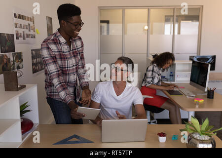 Male executives discussing over digital tablet at desk Stock Photo