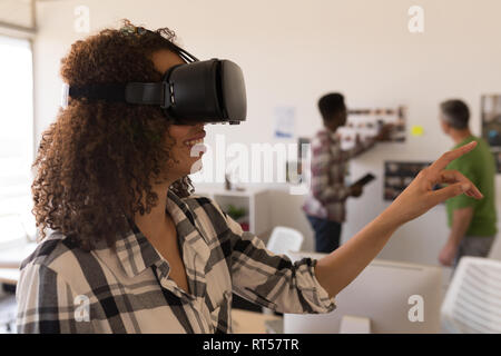 Female executive using virtual reality headset in office Stock Photo