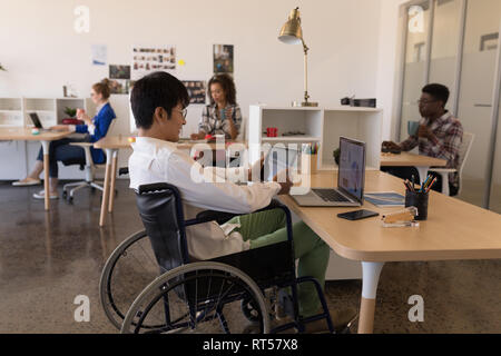 Disabled male executive using digital tablet at desk Stock Photo