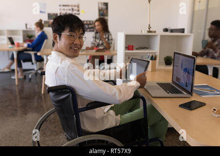 Disabled male executive using digital tablet at desk Stock Photo