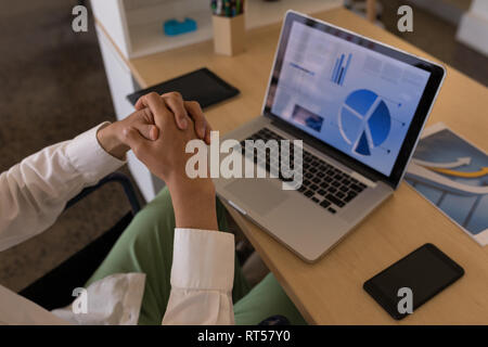 Male executive using laptop at desk in office Stock Photo
