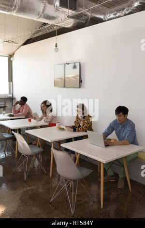 Business colleagues using multimedia devices in canteen Stock Photo
