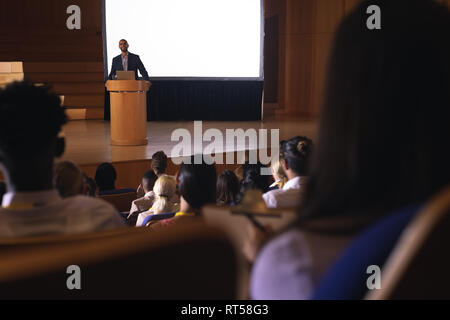 Businessman standing around the podium and giving speech in front of audience in the auditorium Stock Photo