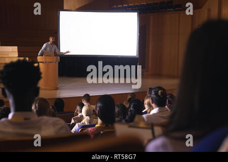 Businessman standing around podium and giving presentation in the auditorium Stock Photo