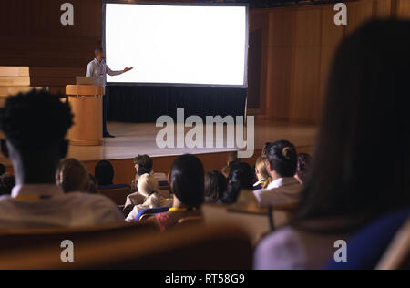 Businessman standing around podium and giving presentation in the auditorium Stock Photo