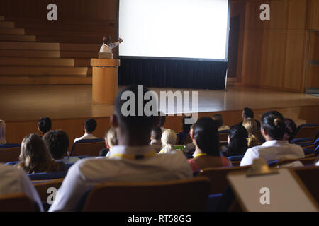 Businessman standing around podium and giving presentation in the auditorium Stock Photo