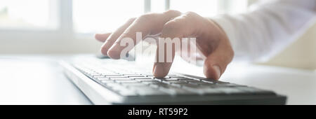 Wide closeup view image of male hand typing on black computer keyboard. Stock Photo