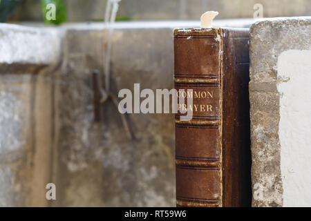 Old leather-bound prayer book with detail of an ancient stone church Stock Photo