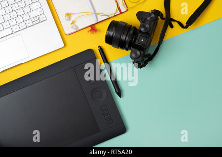 Workplace with graphic tablet in digital work and photo editing, view from above on blue yellow background Stock Photo