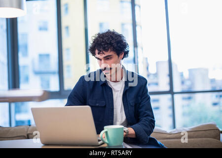 Focused man working at laptop in urban apartment Stock Photo