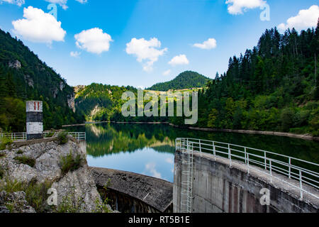 Beautiful aqua and blue colors of the lake Spajici, and the river  Beli Rzav, on the mountain Tara, Green trees and small village houses and dam Stock Photo