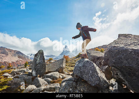 Chile, Cerro Castillo, boy jumping from rock in mountainscape Stock Photo