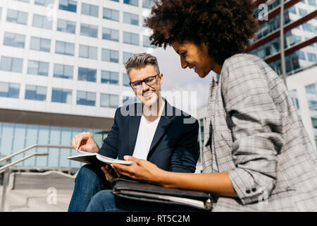 Two happy colleagues working together outside office building Stock Photo