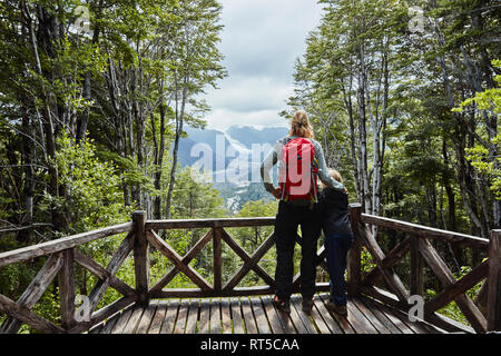 Chile, Chaiten, Parque Pumalin, mother and son on observation deck looking at glacier Stock Photo