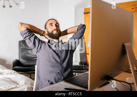 Smiling young man working relaxed at home Stock Photo