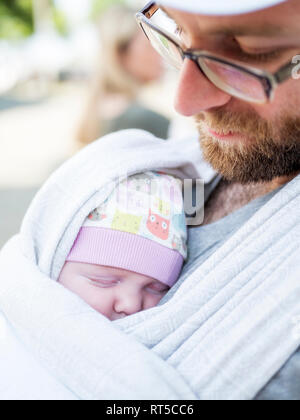 Father carrying his baby daughter on his chest in  a sling Stock Photo