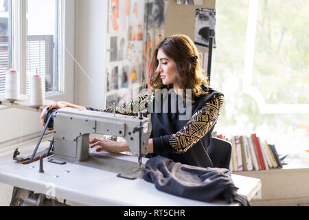 Young designer using sewing machine in an atelier Stock Photo