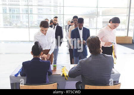 Business people checking in at conference registration table Stock Photo