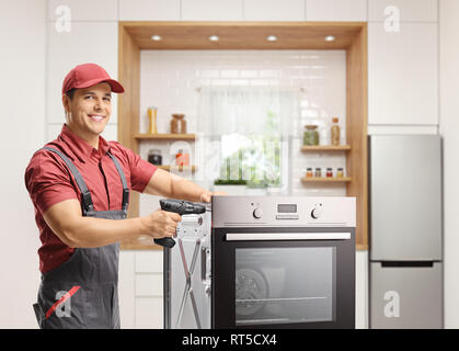 Repairman working with a drill on an oven in a kitchen Stock Photo