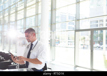 Male doctor using digital tablet in waiting room Stock Photo
