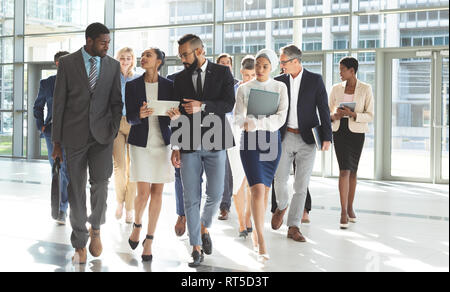 Front view of group of diverse business people walking together in lobby office Stock Photo