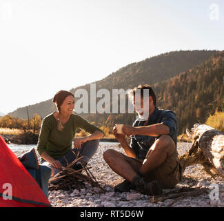 Mature couple camping at riverside in the evening light Stock Photo
