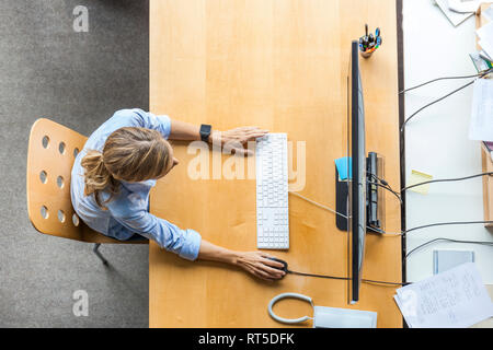 Top view of woman using computer at desk in office Stock Photo
