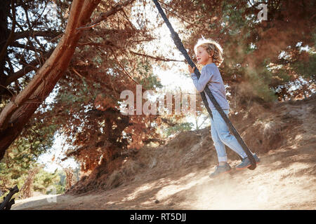 Boy swinging on a rope in backlight Stock Photo