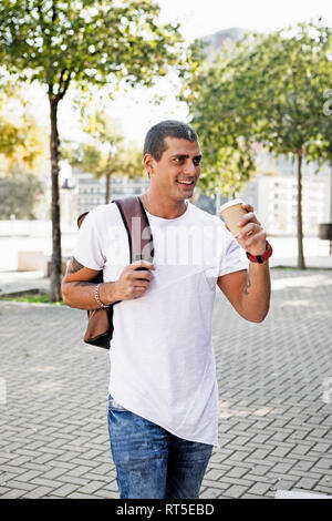 Smiling young man with takeaway coffee on the go Stock Photo