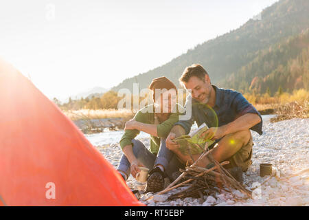 Mature couple camping at riverside, looking on map Stock Photo