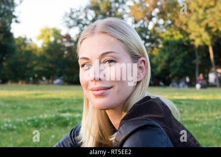 Portrait of content blond woman relaxing in a park Stock Photo