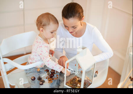 Mother and little daughter tinkering autumnal decorative house at home Stock Photo
