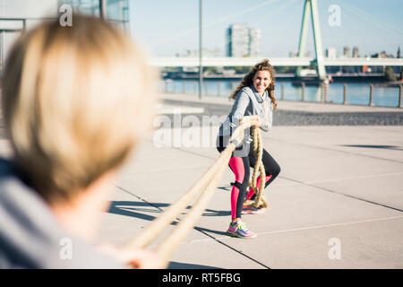 Friends training at the riverside, pulling rope Stock Photo