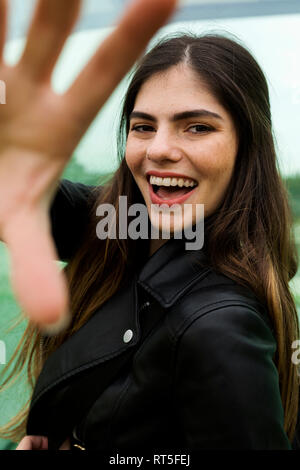 Portrait of happy young woman with long brown hair rasing her hand