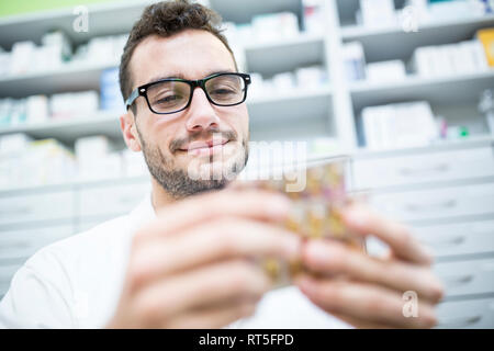 Smiling pharmacist holding tablet package in pharmacy Stock Photo