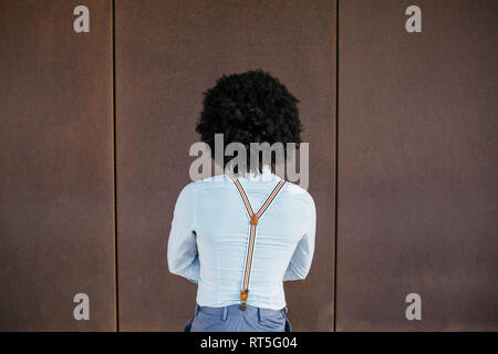 Back view of man wearing shirt and suspenders against rusty background Stock Photo